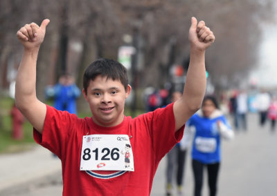 Un adolescent lève les bras dans les airs, fier d'avoir terminé le mini-marathon.