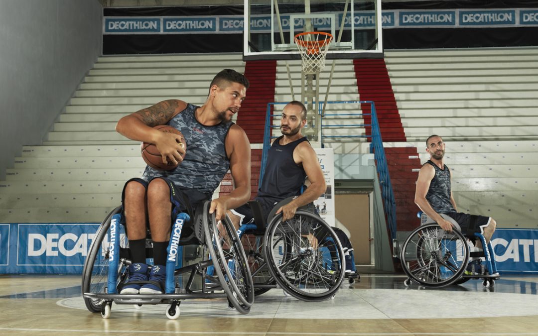 Des athlètes en basket en fauteuil roulant jouent sur un terrain Decathlon.