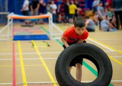 Un garçon soulève un pneu dans le cadre d'une épreuve du circuit fonctionnel.