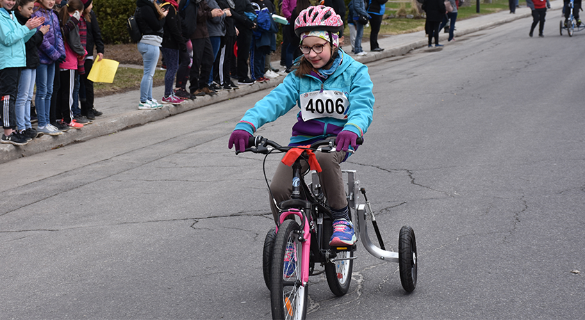 Une fille sur un tricycle participe au mini-marathon.