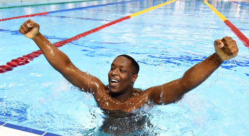 Un garçon fier lève les bras vers le ciel dans une piscine.