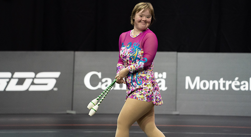 Une fille tient deux bâtons dans ses mains pour sa routine de gymnastique rhythmique.
