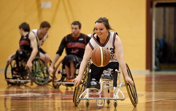 Élodie Tessier manie le ballon pendant un match de basketball en fauteuil roulant