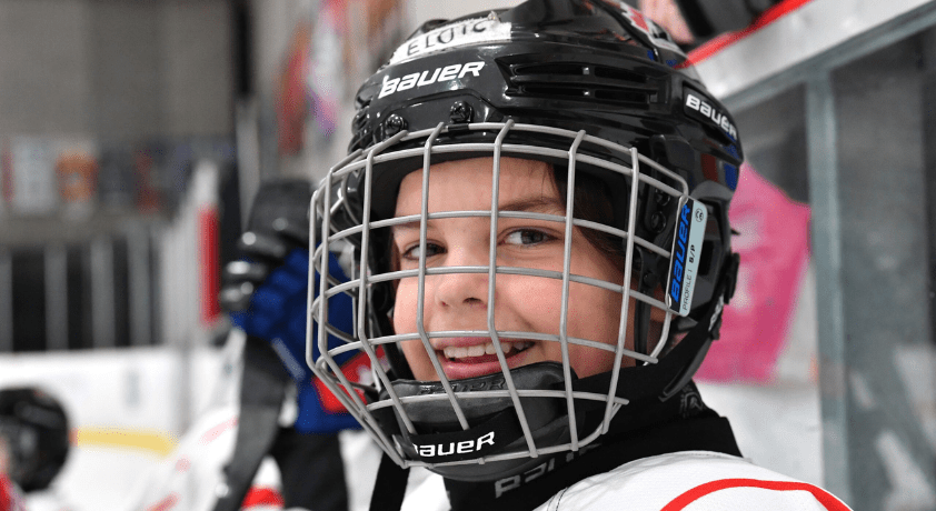Un jeune joueur de parahockey souriant sur le banc des joueurs.