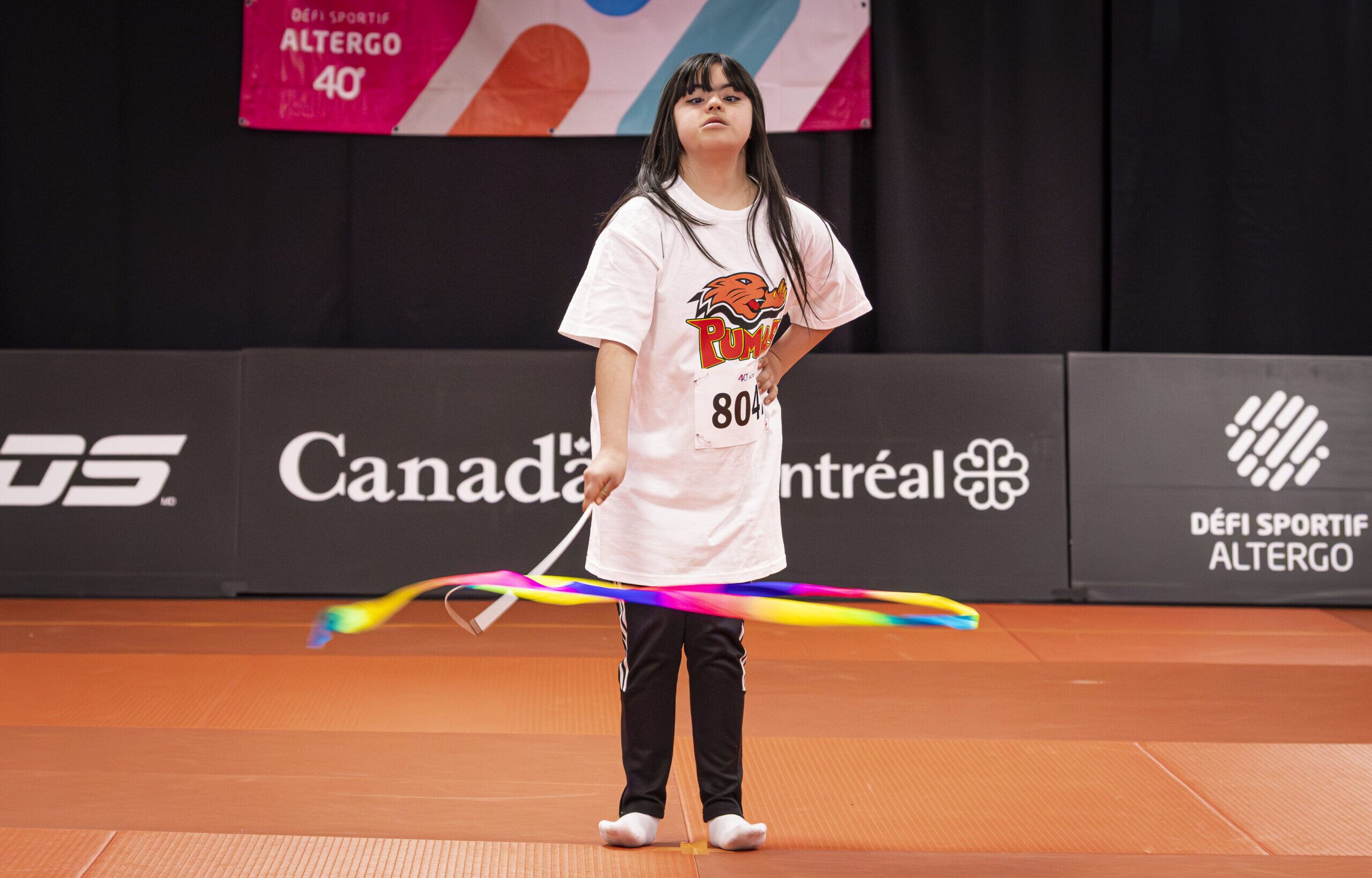 Une jeune athlète qui agite un ruban pendant une épreuve de gymnastique rythmique.