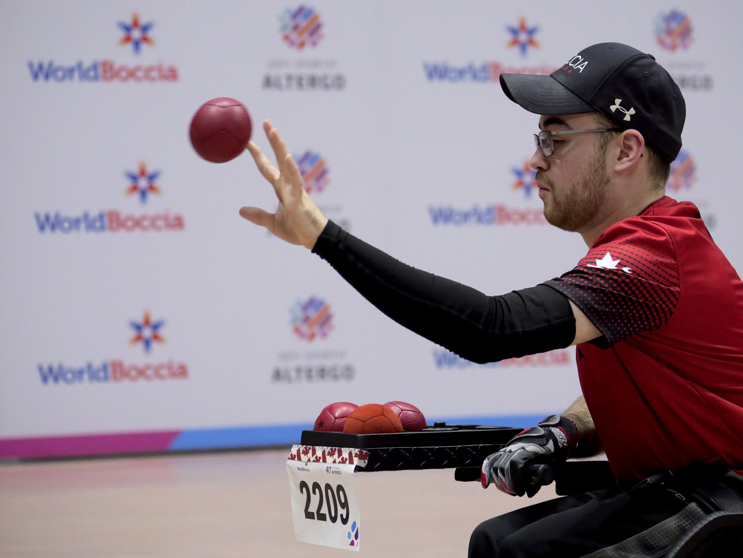 Un athlète en fauteuil roulant lance une balle de boccia.