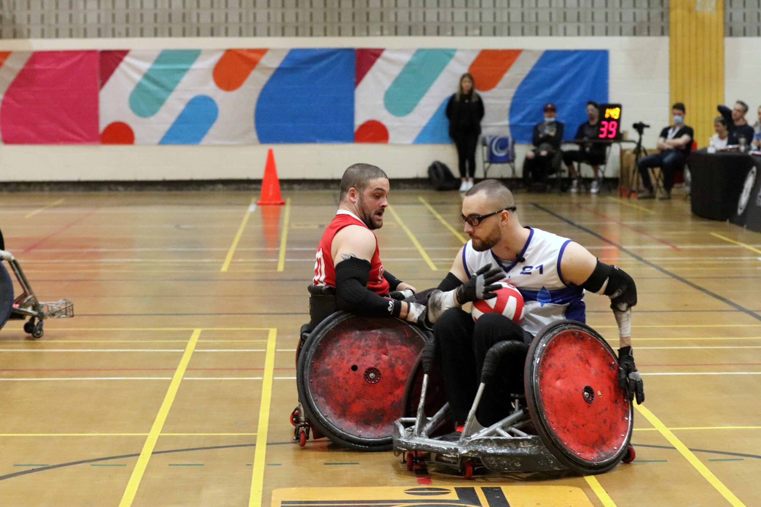 Deux athlètes de rugby en fauteuil roulant se disputent la balle.