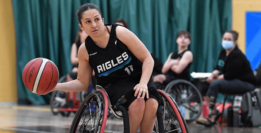 Une joueuse de basketball en fauteuil roulant dribble avec le ballon.
