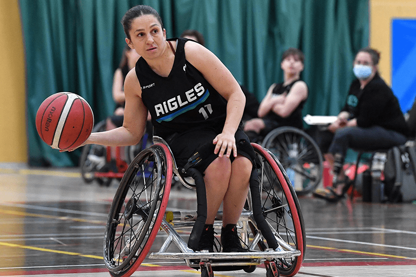 Une joueuse de basketball en fauteuil roulant dribble avec le ballon.