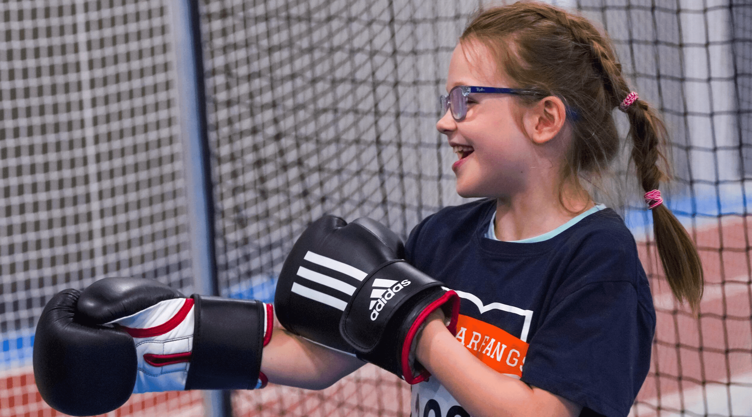 Une jeune fille souriante avec des gants de boxe.