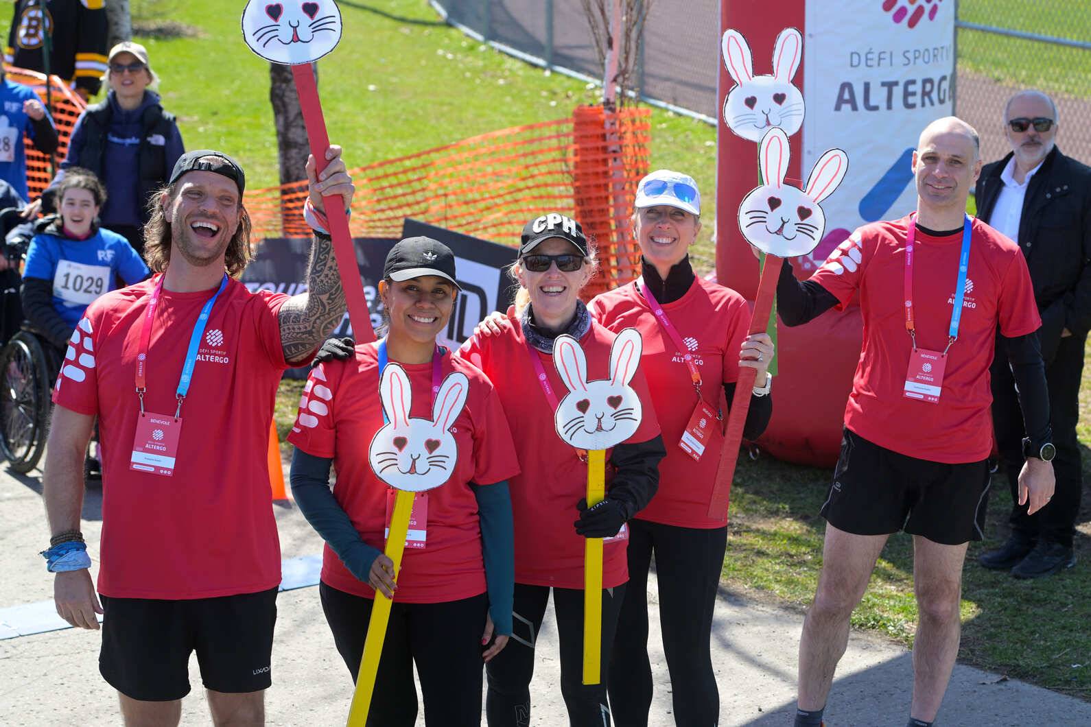 Des bénévoles habillés de t-shirts rouges sourient à la caméra lors d'une compétition extérieure ensoleillée du Défi sportif AlterGo.