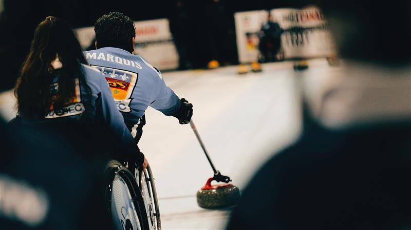 Carl Marquis fait un lancer en curling en fauteuil roulant.