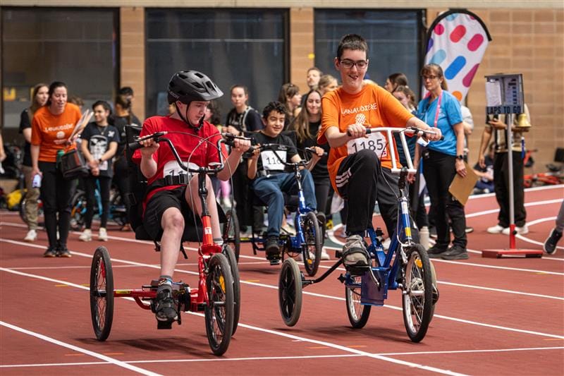 Deux jeunes athlètes font une course en tricycle.