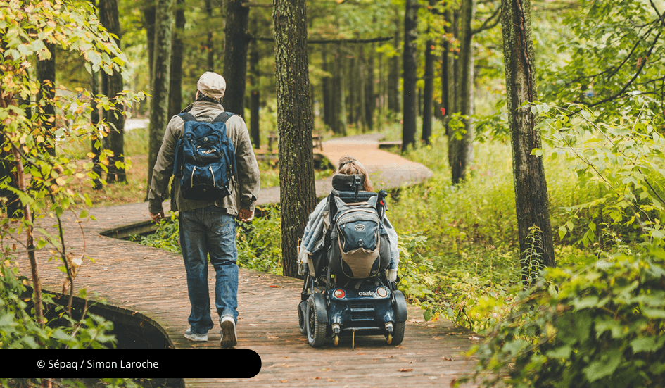 Une personne en fauteuil roulant et une debout sur un sentier accessible.