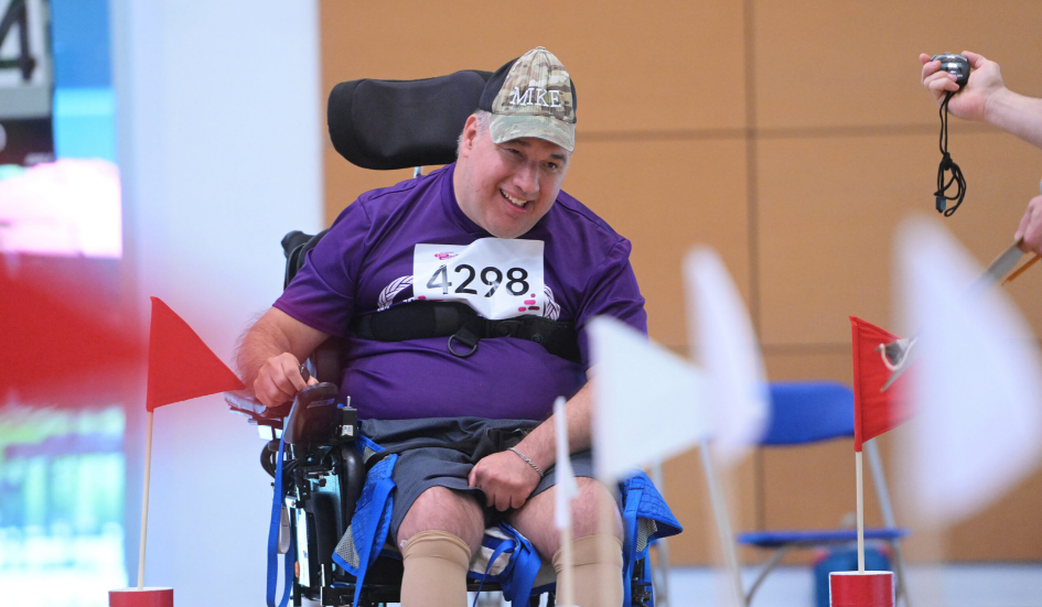 Un homme en fauteuil roulant électrique participe à une épreuve d'athlétisme.